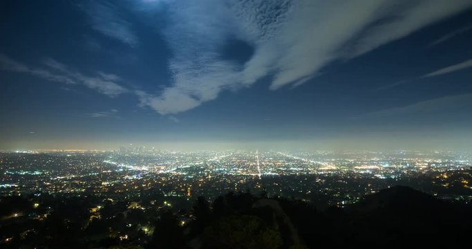 Los Angeles, California, USA - view from Griffith Observatory at City of Los Angeles facing south at clear night with moonlight and a few moving clouds - Timelapse with pan left to right 