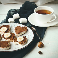 Delicious sweet Breakfast with a Cup of tea, and waffles with chocolate spread, bananas and marshmallows