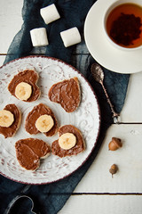 Delicious sweet Breakfast with a Cup of tea, and waffles with chocolate spread, bananas and marshmallows