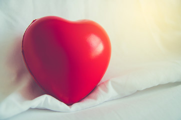 Red heart shaped on white bed