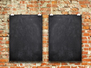 Two blank black blackboard frames hanged by clips against orange weathered brick wall background
