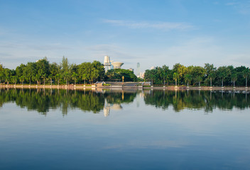 the green park in city reflection from water in lake.