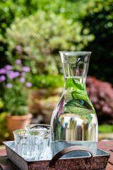 Karaffe mit aromatisiertem Kr&auml;uterwasser auf Gartentisch