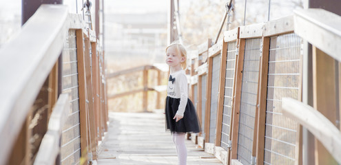 Little Girl Stands on a Suspension Bridge