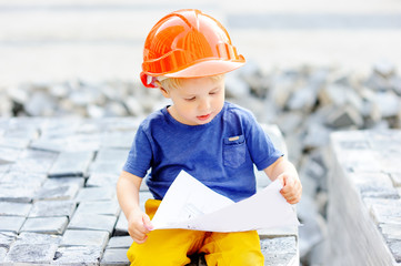 Portrait of little builder in hardhats reading construction drawing