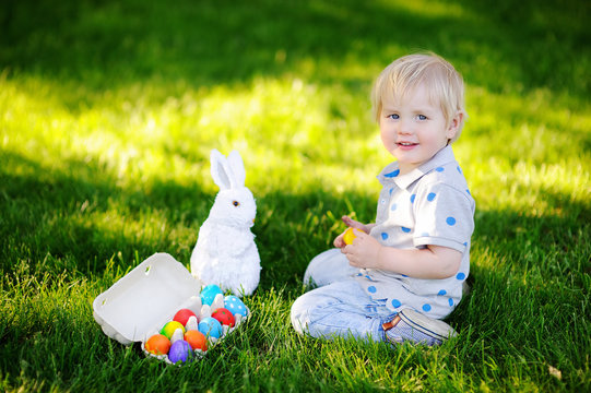 Little boy hunting for easter egg in spring garden on Easter day