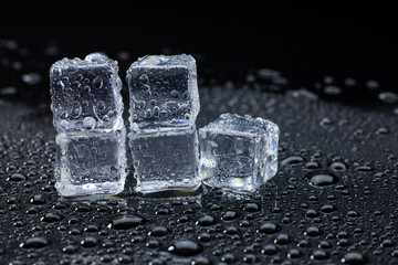 Wet ice cubes and water drop on black background.