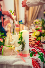 white candle burn, standing on table, near  bottles of champagne for newlyweds