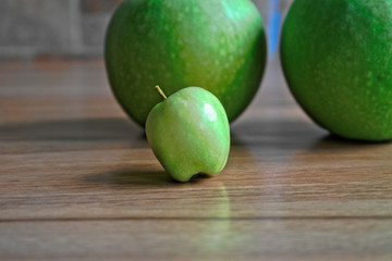 Tiny green apple on a wooden table