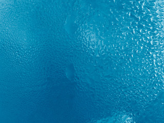 Naklejka na ściany i meble Blue water drop on glass windows background