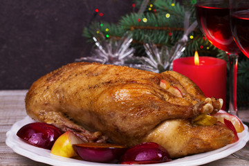 Festive Christmas duck  with plums and apples, glasses of red wine; candles