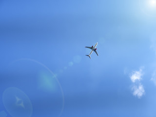 Flying plane in blue sky with sunray