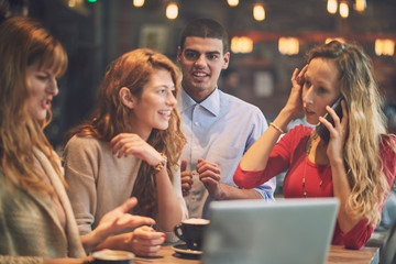 Four friend in the cafe, watching laptop, right one is talking over phone