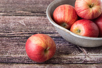 Apples.   Red ripe apples in an old aluminum bowl on a wooden table.