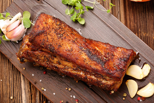 Fried pork ribs with herbs on wooden background