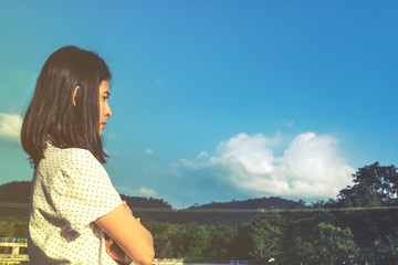 pretty young asian girl standing and thinking under blue sky, th
