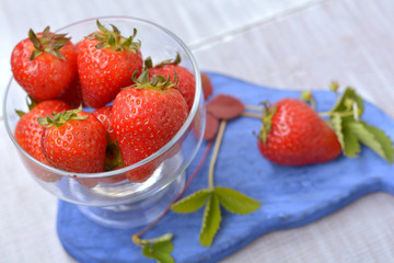 Transparent dish full of aromatic strawberries close up