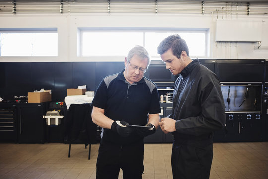 Senior mechanic and expert using digital tablet at auto repair shop