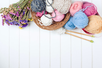Knitting yarn balls and needles on white wooden background.