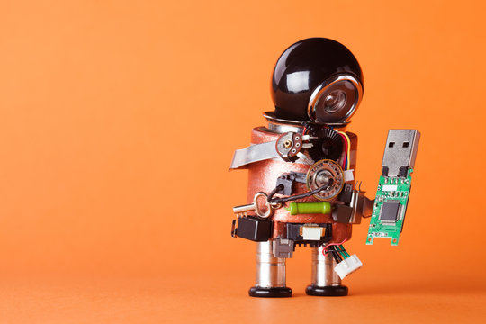 Robot with usb flash storage stick. Data storing and robotic technology concept, fun toy character black helmet head. Copy space, orange background, macro view soft focus