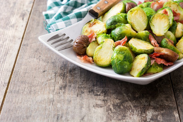 Brussels sprouts with chestnuts and bacon on wooden table
