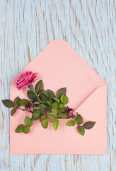 Top view of a pink envelope with rose flower in it