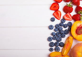 Fototapeta na wymiar Blueberries, strawberries and peaches on the white table