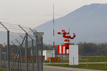 Mobile military radar equipment at airport by barbwire chain link fence