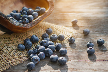 Bowl of blueberries in morning light. Blueberries on wooden background.