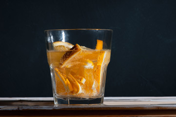Refreshment Detox water with orange Cocktail with air bubbles and a splash on a black background of a concrete wall