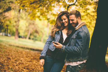 Fototapeta premium Couple with phone in autumn park