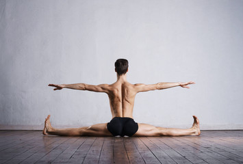 Handsome ballet dancer sitting on splits