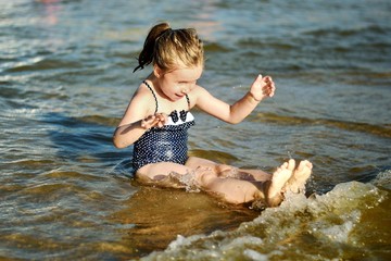 Adorable little girl is splashing and smashing sea water and having fun