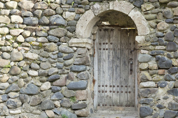 Fototapeta na wymiar An old wooden door at the entrance to an ancient church in a sto