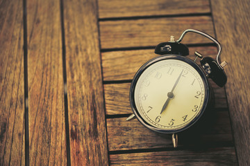 old clock at 6 o'clock on wooden table vintage color tone.