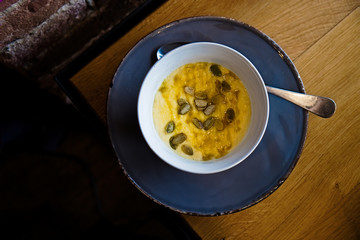 Healthy polenta porridge bowl with pumpkin seeds and honey on a grey plate. Warm autumn and winter breakfast. Wooden table. Top view