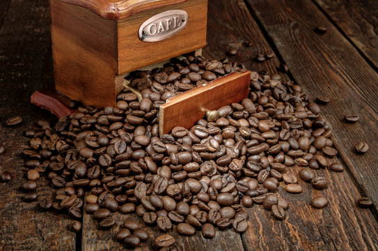 Close-up coffee grains with grinder on dark rustic background