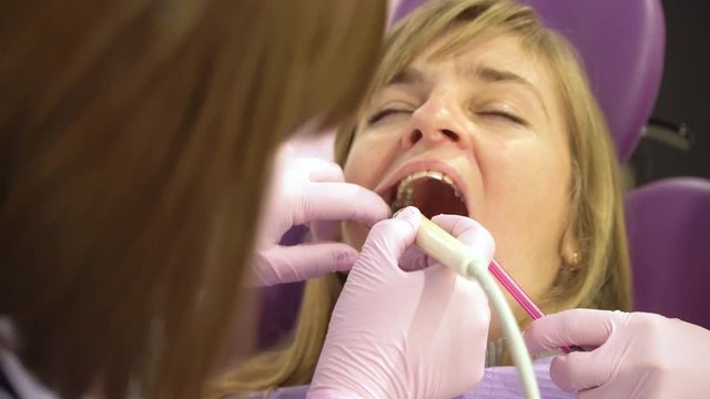 Woman at the dental hygienist and dentist clinic professional tooth whitening and ultrasound cleaning. Odontic and mouth health and hygiene is important part of human life that dentistry help with