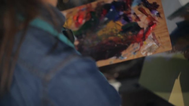 Girl artist paints with oil painting.