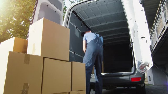 Delivery Man Loads Cardboard Boxes into his Van. Slow Motion. Shot on RED Cinema Camera in 4K (UHD).