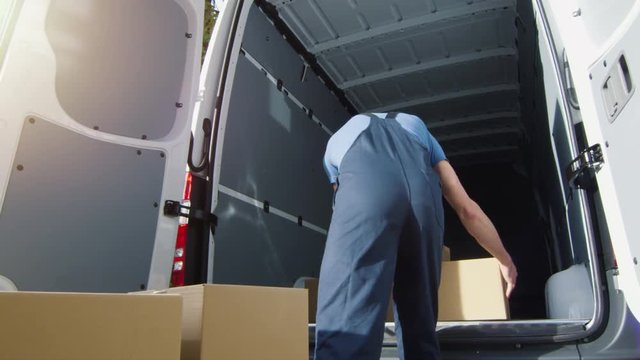 Delivery Man Loads Cardboard Boxes into his Van. Slow Motion. Shot on RED Cinema Camera in 4K (UHD).
