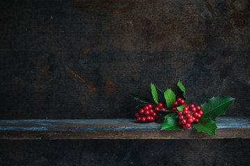 Christmas decoration with red berries placed on a wooden shelf.