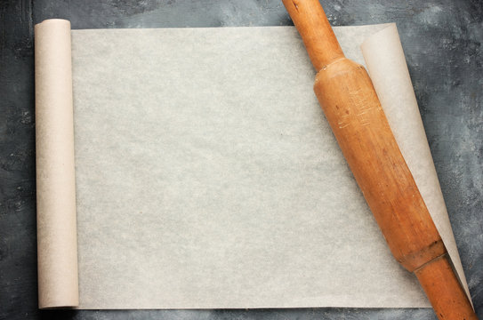 Open roll of baking parchment paper with rolling pin
