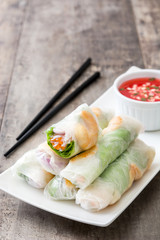 Vietnamese rolls with vegetables, rice noodles and prawns on wooden background
