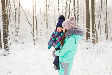 Fototapeta na wymiar Young brunette mother with her daughter outdoors. Winter time