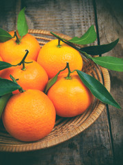 Ripe tangerines in the basket on wooden background. selective focus.