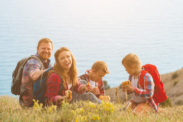 Family of four people eating fastfood in mountains
