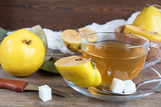 The cup of hot  tea and fresh quince fruit on dark wooden table. An autumn still life. 