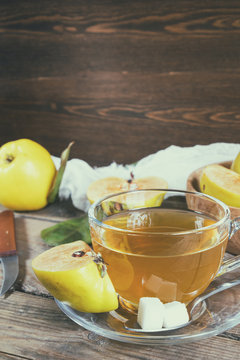 The cup of hot  tea and fresh quince fruit on dark wooden table. An autumn still life. Coloring and processing photo