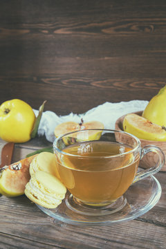 The cup of hot  tea and fresh quince fruit on dark wooden table. An autumn still life. Coloring and processing photo